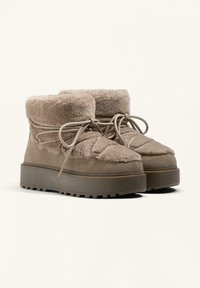 Botine din suede maro la glezna, cu un guler pufos din blană sintetică, vârf rotund și design cu șireturi, pe o talpă platformă înălțată.