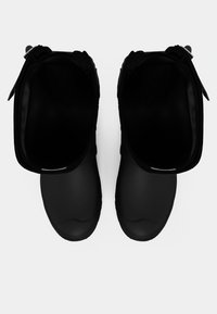 Μαύρα καουτσούκ μπότες με λεία υφή, στρογγυλή μύτη και φαρδιά ανοίγματα. Διαθέτουν μινιμαλιστικό σχέδιο χωρίς εμφανή διακοσμητικά στοιχεία ή μοτίβα.