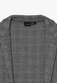 Blazer grigio con un motivo a quadri testurizzato, dotato di colletto e etichetta all'interno. Il materiale sembra intrecciato con un design strutturato.