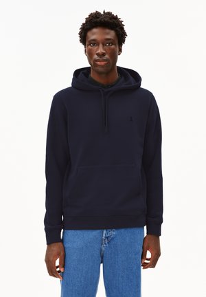 Marineblaue Kapuzenjacke aus weichem Stoff, mit einer Kängurutasche, gerippten Bündchen und einer Kordelzugkapuze. Dezentes Logo auf der Brust.