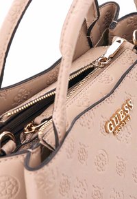 Borsa beige con design del logo embosso, dotata di hardware dorato, un compartimento con zip e rifiniture nere a contrasto. Texture liscia.