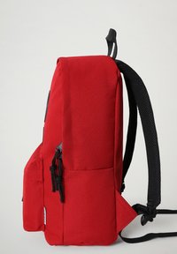 Roter Rucksack mit schwarzen Trägern, aus strapazierfähigem Gewebe. Verfügt über eine Vordertasche mit Kordelzug, glatter Textur und schlichtem Design.