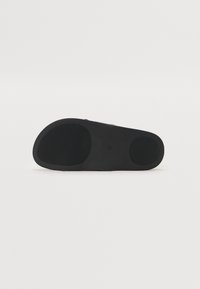 Black shoe sole with a smooth, textured surface. Features two circular treads for grip and a rounded toe design.