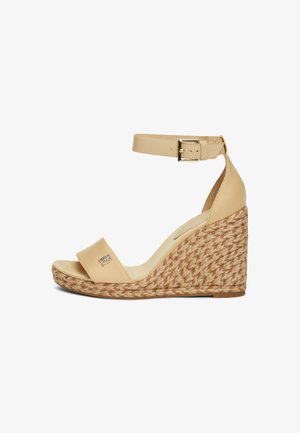 Sandalias de cuña de cuero beige con tacón de yute trenzado, que cuentan con una tira suave sobre los dedos y una correa de tobillo segura con una hebilla de metal.
