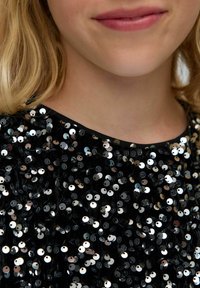 Mustmust toode, millel on mustad sädelejad detailid ja ümmargused metallist kaunistused, ümar kaelus ja pehme tekstuur, rõhutades säravat ja sügavat efekti.
