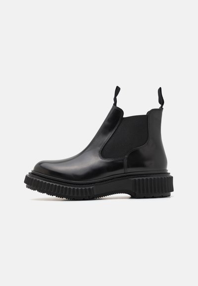 Botas Chelsea de cuero negro con paneles laterales elásticos, tiradores, suela de goma gruesa, punta redondeada y textura estriada.
