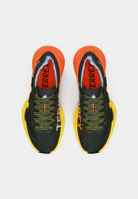 Αθλητικά παπούτσια σε μαύρο και κίτρινο με πορτοκαλί λεπτομέρειες, επάνω μέρος από δίχτυ, υφή στη σόλα και πολύχρωμα κορδόνια με την επωνυμία «TERREX».