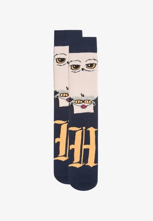 Calcetines azul marino con un diseño de un búho blanco sosteniendo una carta sellada y texto estilizado en amarillo en la parte inferior.