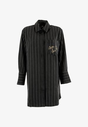 Maglietta a righe bianche e nere con maniche lunghe, colletto e taschino sul petto con testo in corsivo dorato. Tessuto di cotone.