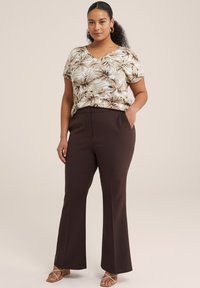 Top de manga corta con estampado floral en beige y marrón, combinado con pantalones acampanados marrón oscuro y tacones de tiras en color tostado. Texturas suaves, diseño casual.