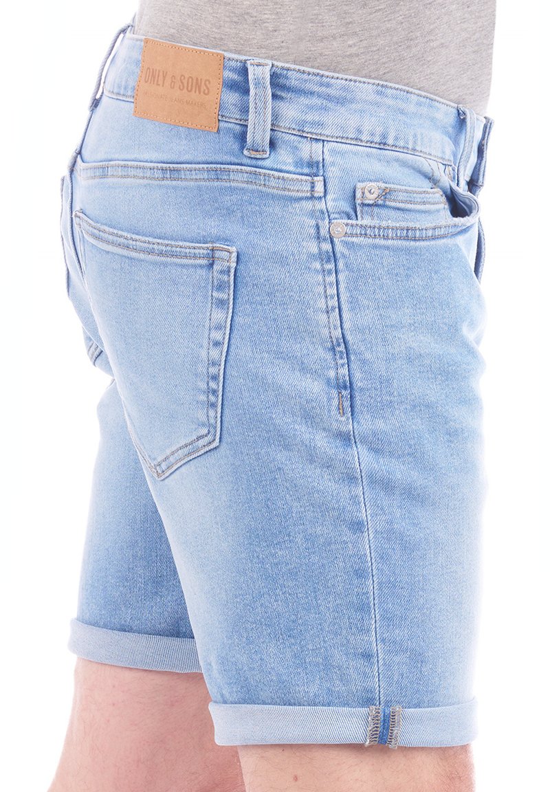 Pantalones cortos de denim azul claro con dobladillo enrollado, que cuentan con bolsillos traseros, un parche de cuero en la cintura y un diseño clásico de cinco bolsillos.
