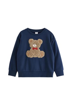 Sweat-shirt bleu marine à manches longues avec un ours en peluche texturé portant un nœud papillon rouge centré sur le devant.
