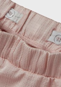 Rosa strukturierter Stoff mit einem gerafften Taillenbund. Verfügt über Knopfverschlüsse und ein glänzendes Finish. Glattes Material mit minimalen Falten.