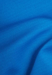 Jasnoniebieska dziana tkanina o teksturowej powierzchni, ukazująca gładki, elastyczny wygląd oraz subtelny wzór małych, równomiernie rozmieszczonych włókien.