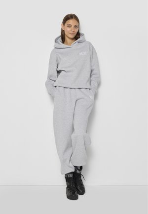 Szare dresowe spodnie i dopasowany hoodie wykonane z miękkiej mieszanki bawełny. Hoodie ma kieszeń z przodu oraz logo na klatce piersiowej.