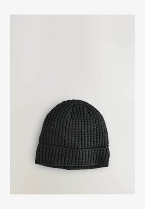Fekete kötött sapka bordázott textúrával és hajtott gombsorral, szoros kötésű kialakítással. Nincsenek látható minták vagy díszítések.