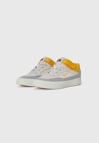 Sneakers med en beige ovandel och grå mocka detaljer, gul rem och vit gummi sula. Inkluderar svart logotyp på tungan.