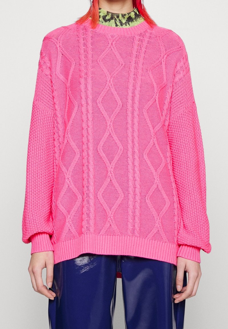 Ljusrosa stickad tröja med ett kabelmönster, ribbade ärmslut och nederkant. Oversized passform med en texturerad design som ger dimension.