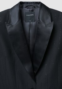 Blazer noir avec une finition satinée, présentant des rayures fines, des revers aigus et une fermeture à un seul bouton. L'étiquette indique "CALLIOPE", taille S.