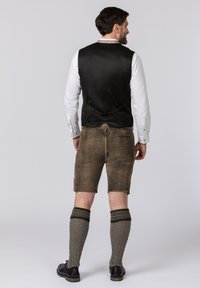 Traditional men's outfit featuring a black satin vest, white shirt, brown shorts, and knitted gray socks with dark accents, paired with black shoes.