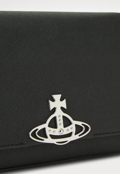 Melna teksturēta maka ar sudraba metāla logotipu, kas attēlo kroni virs orbītas un divām horizontālām gredzenām. Gluda virsma un elegants dizains.