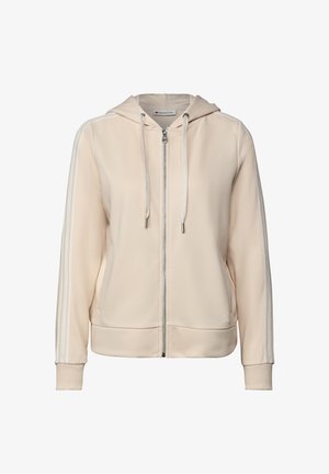 Sweat à capuche zippé beige avec des rayures blanches sur les manches, cordons de serrage sur la capuche, poignets côtelés et poches latérales.