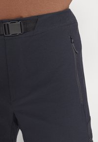 Pantaloni outdoor blu navy con una texture liscia, dotati di una tasca laterale con zip e una cintura regolabile per una vestibilità sicura.
