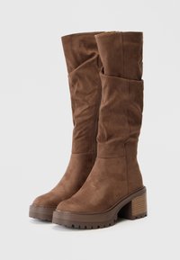 Brown, suede knee-high boots with slouchy design. Chunky heel with horizontal grooves, textured surface, and side zipper.