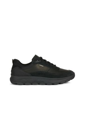 Zapatos deportivos negros que presentan una combinación de cuero liso y gamuza, con forma redondeada, cordones y una suela de goma texturizada.