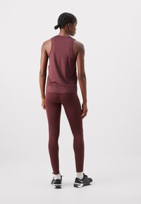 Márvány mintás ujjatlan felső és leggings szett, szoros fazon, sima anyag, fényes textúra, fekete sportcipővel és világos színű zoknikkal párosítva.