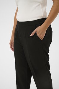 Pantalon noir avec une ceinture élastique, des poches latérales et une texture lisse. Le design présente une coupe décontractée et de légers plis.