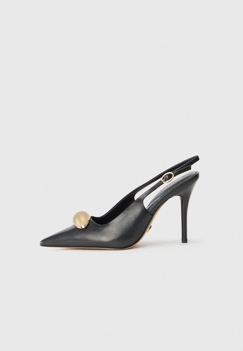 Mustast nahast slingback-tasapinna kingad terava varbaga, kuldne pallikujuline aksessuaar ja peen kont. Üksikasjades on välja lõigatud disain sinna, kus pahkluu.