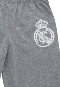 Graue Stoffshorts mit einem weißen Logo des Fußballvereins Real Madrid, das sich mit einer Krone im oberen linken Oberschenkelbereich befindet.