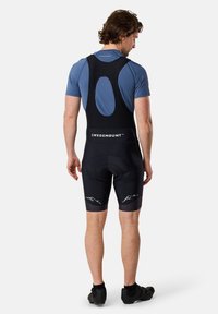 Herrcykelbyxor med hängslen i svart tyg, en åtsittande passform och en logotyp på midjebandet. Har en vadderad sits och mesh bak för ventilation.
