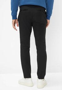 Chino neri con una vestibilità slim, texture liscia e due tasche posteriori. Abbinati a un felpa blu e sneakers bianche.