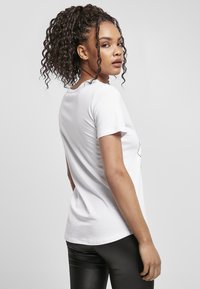 Hvit t-skjorte med korte ermer, rund hals og en tettsittende design, kombinert med svarte leggings. Glatt stofftekstur og enkel stil.