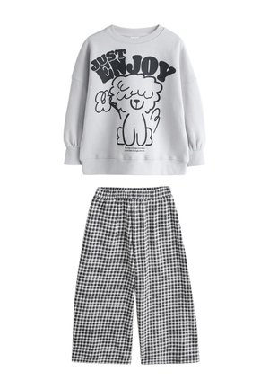 Sweat-shirt gris avec texte "Just Enjoy" et graphique chien, assorti à un pantalon large à carreaux noir et blanc avec taille élastique.