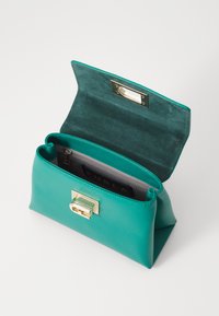 Teal læderhåndtaske med en struktureret form, pyntet med guldfarvet lukning og en åben klaff, der afslører et gråt interiør med et brandlabel.