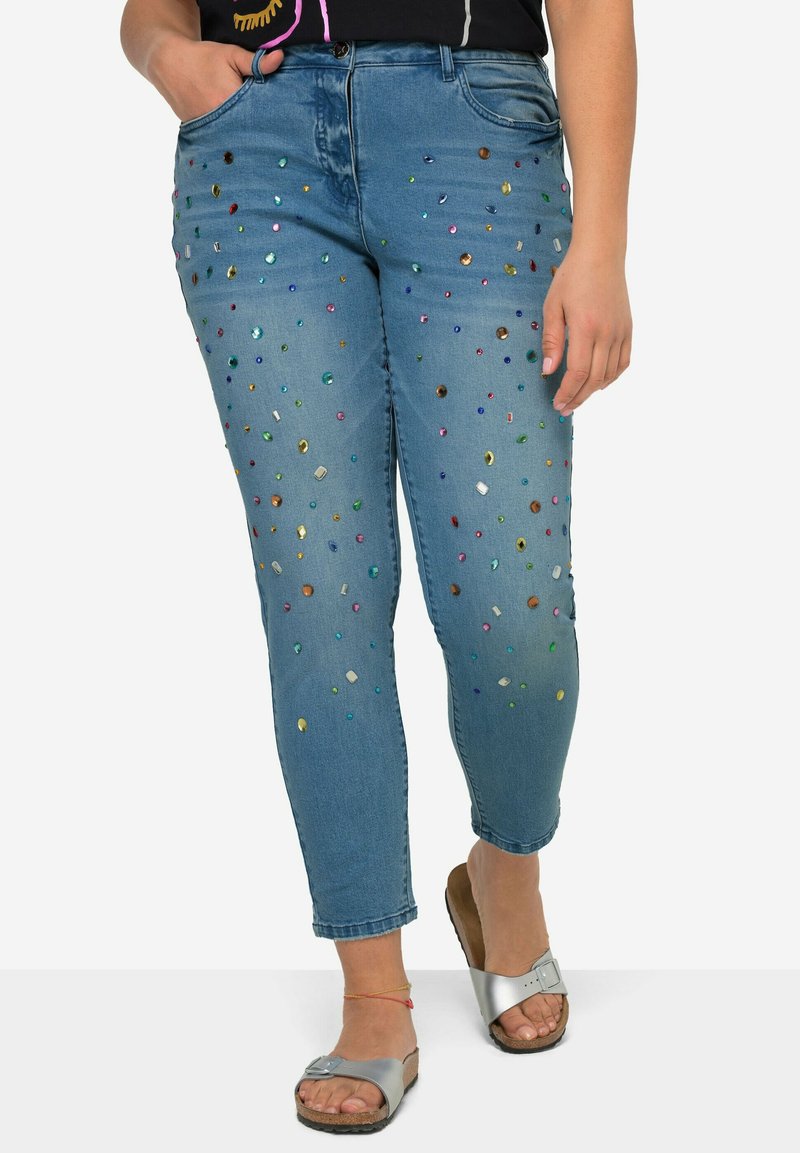 Jeans in denim di colore azzurro chiaro, taglio slim, con decorazioni di strass multicolori sul davanti. Completati con tasche standard.