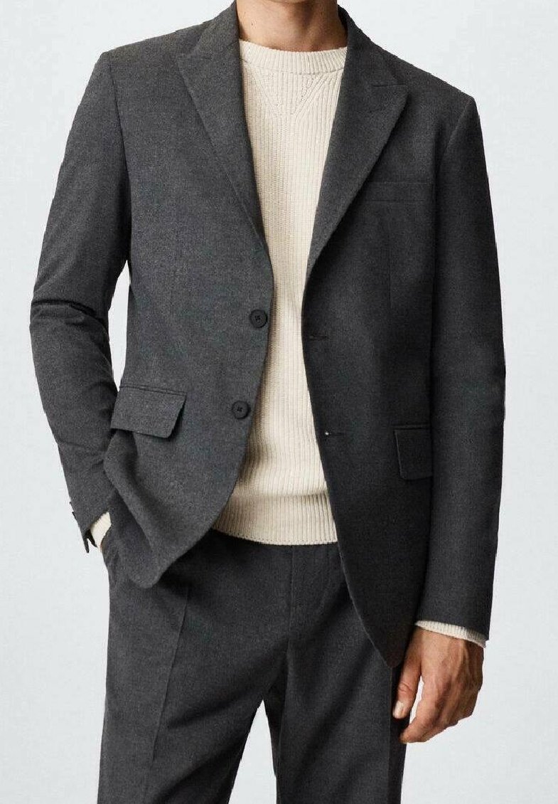 Blazer en laine gris avec revers crantés, deux boutons et une poche poitrine, assorti à un pull crème texturé et un pantalon gris assorti.
