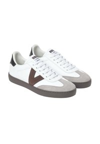 Zapatillas blancas con una puntera de ante gris, detalles en cuero marrón, cordones blancos y un logo en forma de V marrón en el costado. Suela de goma.
