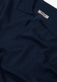 Polo shirt blu navy realizzato in morbido tessuto a maglia. Presenta una chiusura a tre bottoni, colletto a costine e una texture liscia con dettagli minimi.