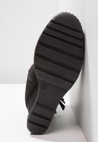 Stivale in suede nero con suola in gomma testurizzata, dotato di tacco piatto e motivo a zigzag. Chiusura laterale con zip e nappine decorative visibili.