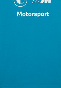 Turkio spalvos medvilnės marškinėliai su baltais logotipais ir tekstu, įskaitant "BMW" ir "Motorsport". Lygi tekstūra, klasikinis apvalus kaklo išpjovimas, trumpomis rankovėmis.