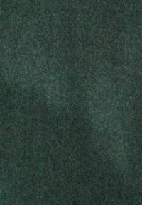 Tessuto in feltro verde scuro con una texture morbida e pelosa e sottili variazioni di sfumatura su tutta la superficie.