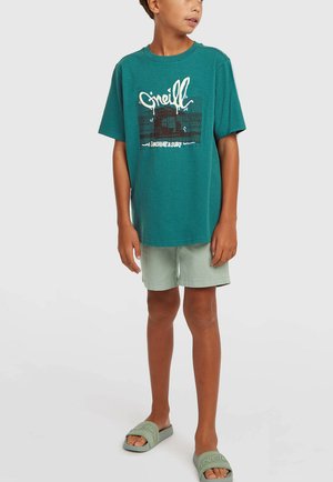 Modré bavlnené tričko s bielym grafickým textom a dizajnom, doplnené svetlozelenými šortkami a zodpovedajúcimi šľapkami. Neformálny, pohodlný strih.