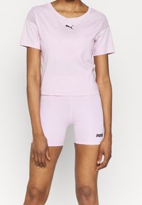 Rosa bomullströja med korta ärmar och rundad halsringning, med en svart Puma-logotyp. Kombination med matchande rosa shorts som visar Puma-namnet.
