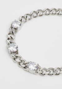 Bracciale in argento con tre strass trasparenti e rotondi montati su prigionieri metallici, con anelli ovali intrecciati e una finitura lucida.