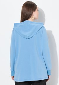 Světle modrá mikina s kapucí a dlouhými rukávy, s žebrovanými manžetami a spodním lemem. Měkký materiál s volným střihem, viditelné švy.