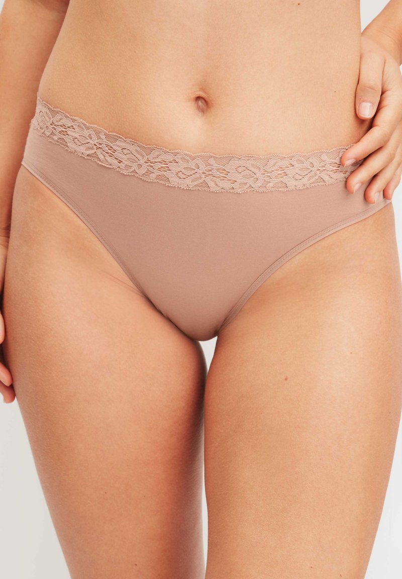 Culotte de bikini nude en tissu extensible et lisse. Dotée d'une ceinture en dentelle avec des motifs floraux. Design minimaliste avec une coupe classique.